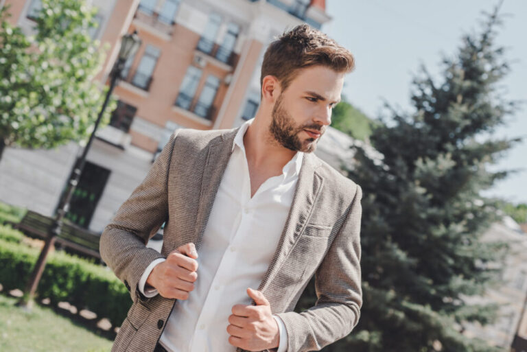 Busy man. Serious brown-haired man standing in the park in the morning going to work